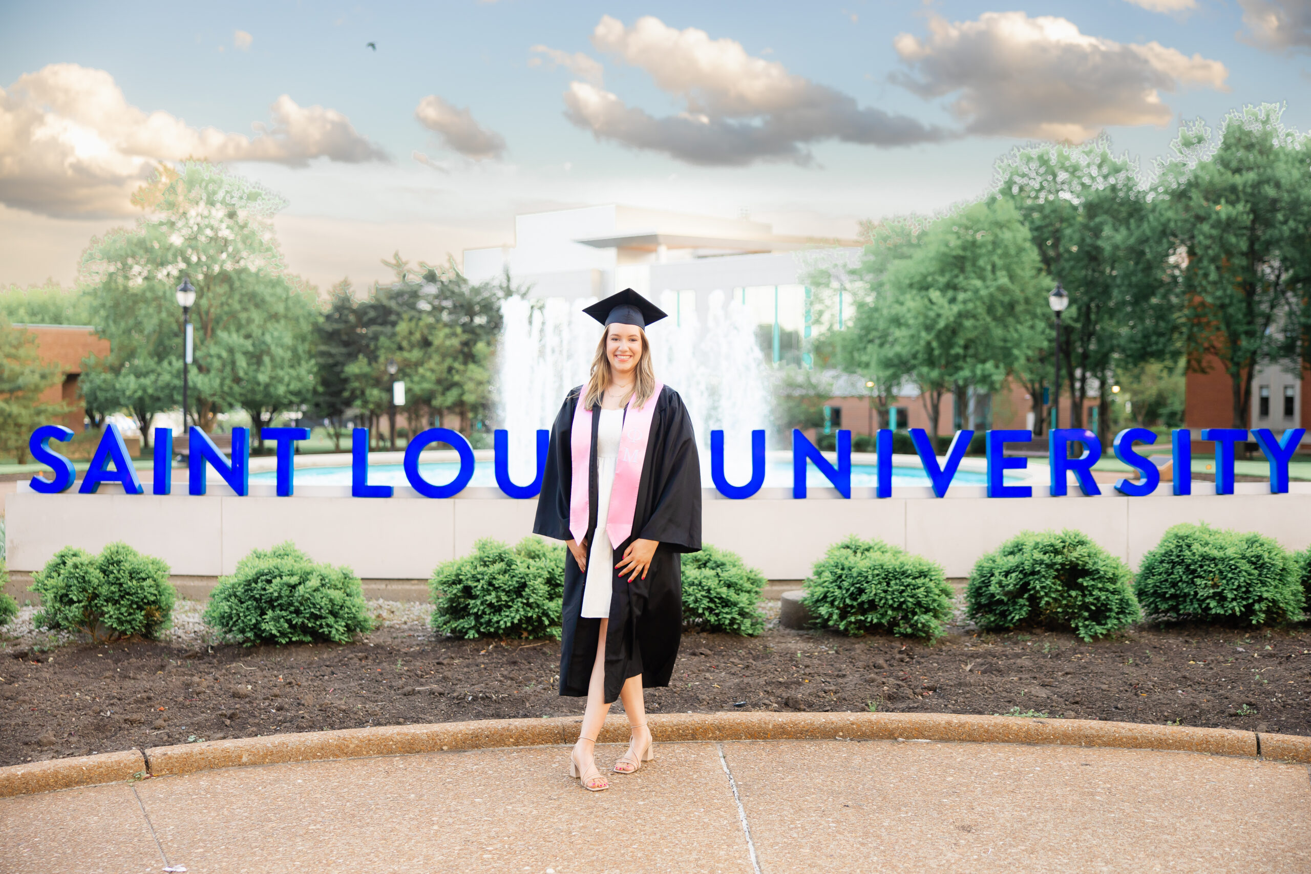 SLU senior in front of the Saint Louis University Sign on campus