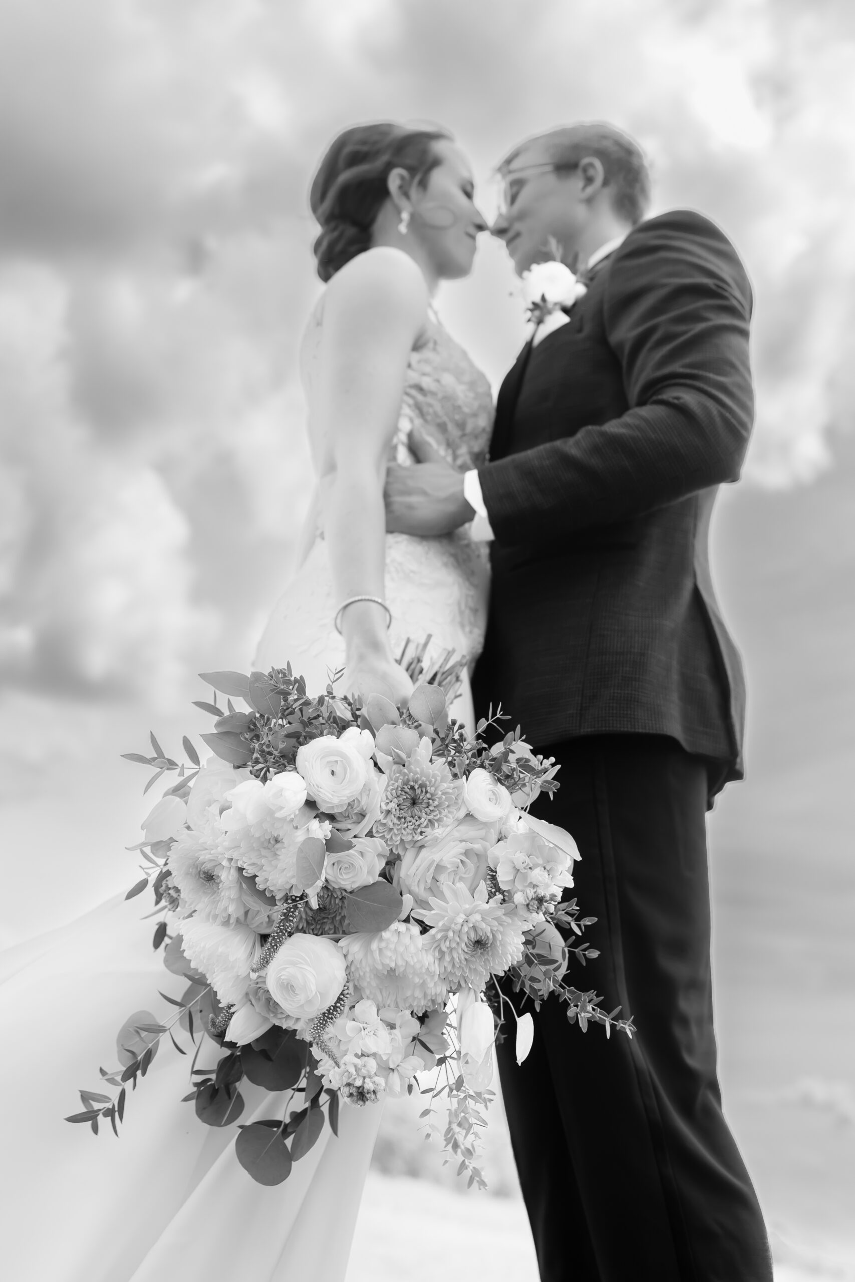 black and white photo of close up bouquet in focus and couple out of focus